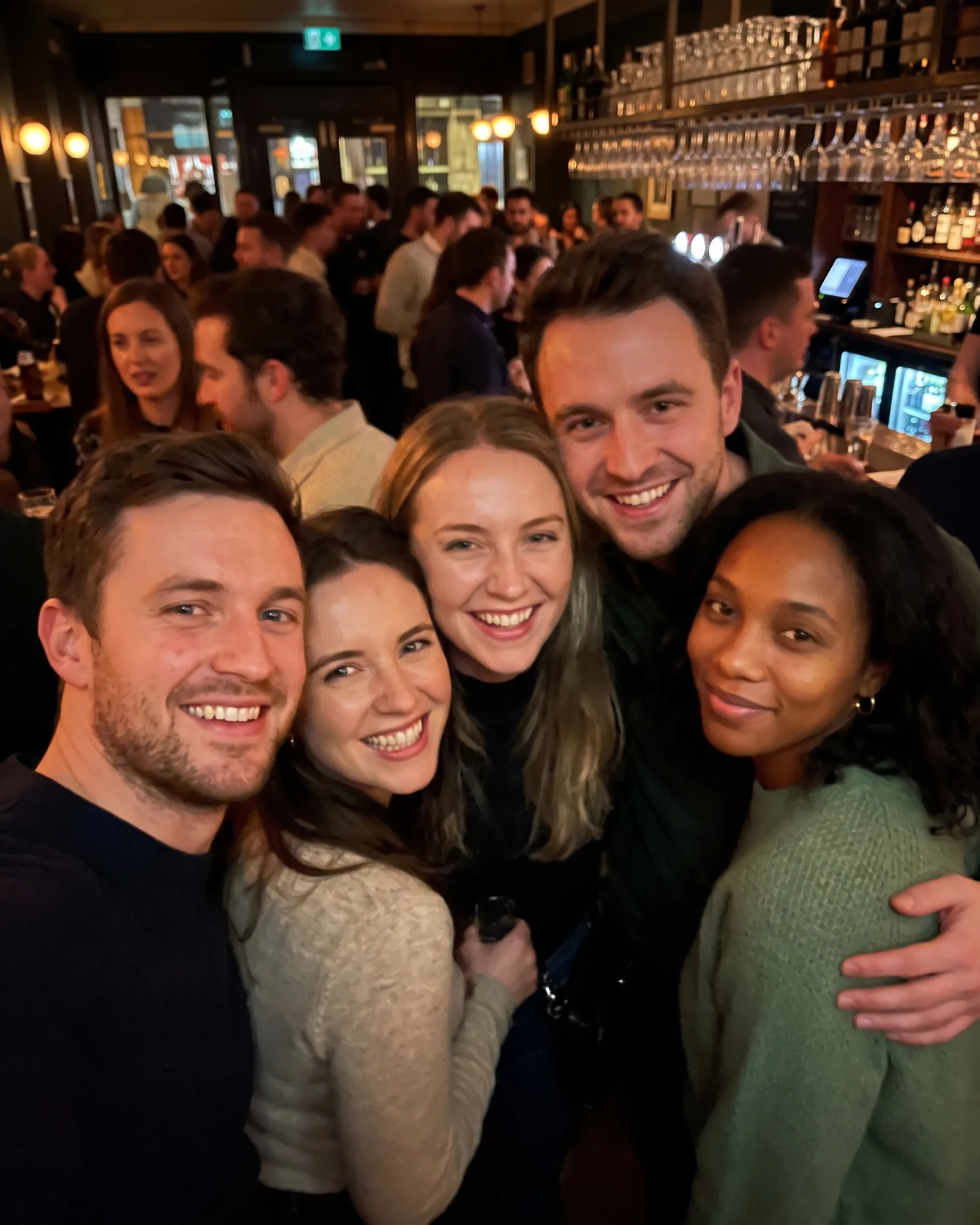 The same woman at the far right of a group of five friends in a bar.